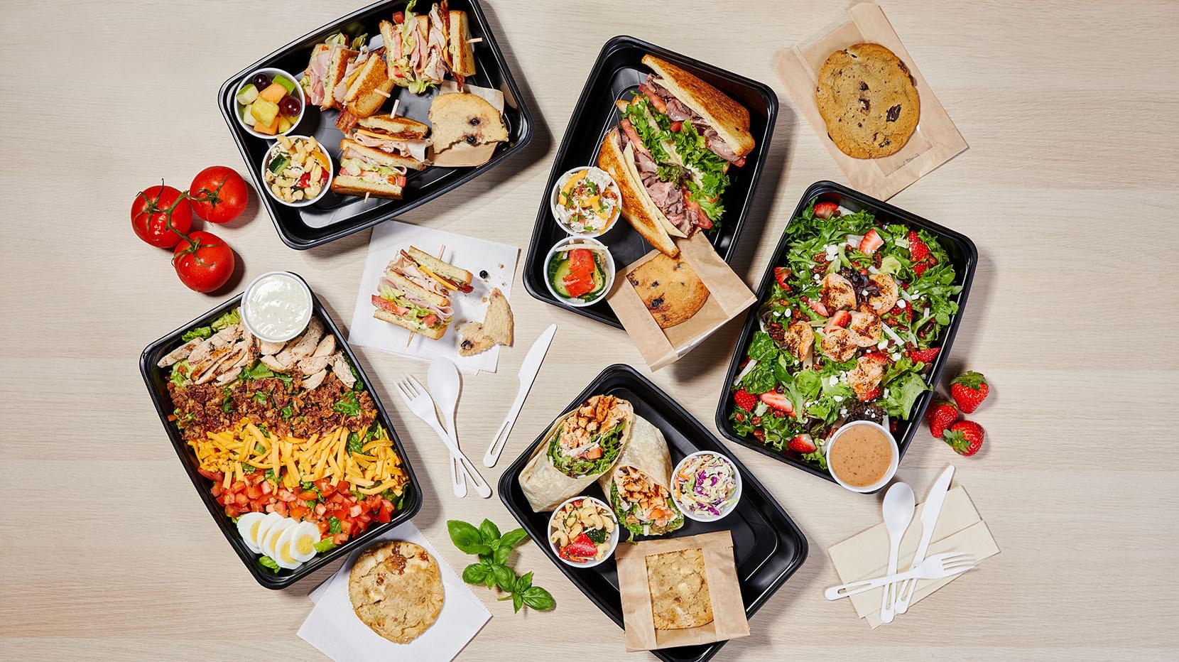 Five platters of Firebirds catered meals spread on a table.